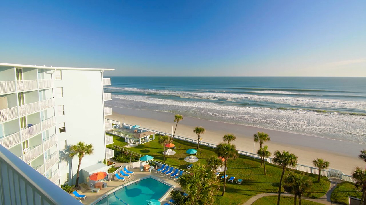 A beachfront hotel with a pool and palm trees